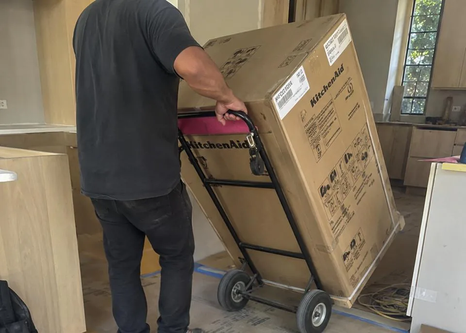 Appliance repair technician servicing a refrigerator in a Solana Beach coastal home kitchen
