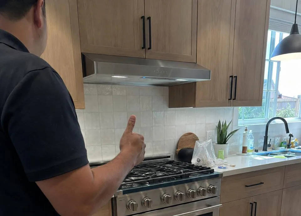 Appliance technician fitting a modern wall oven into an original mid-century kitchen cabinet in a La Mesa, CA home