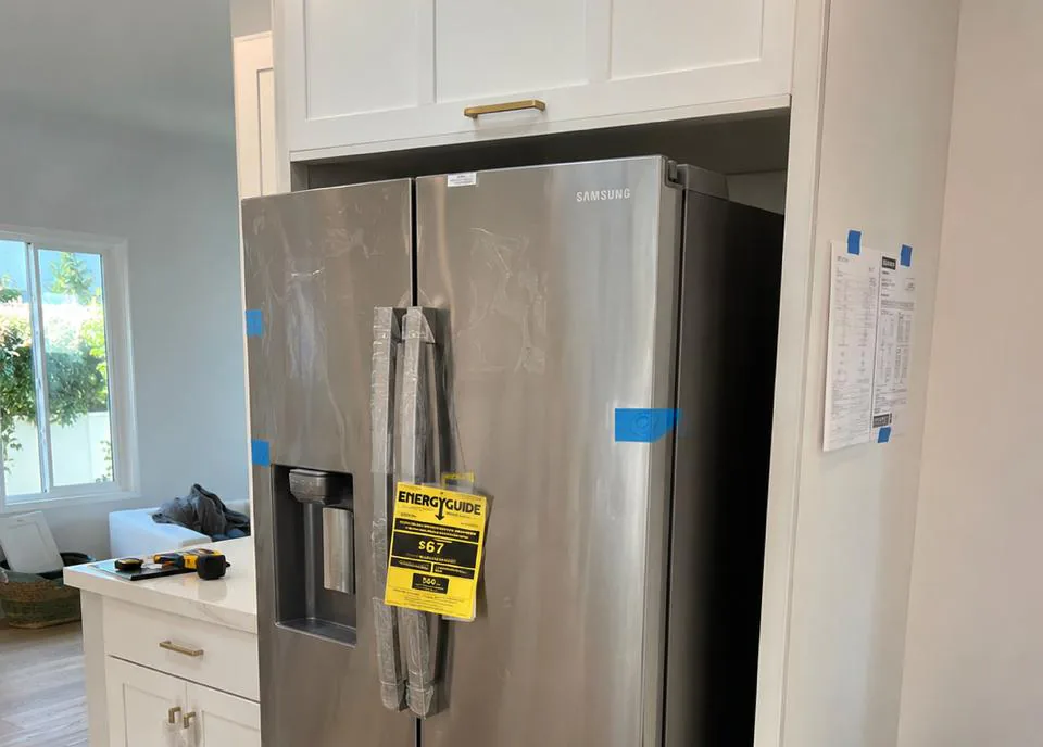 Appliance repair technician servicing a refrigerator in an Escondido, California home in inland North County