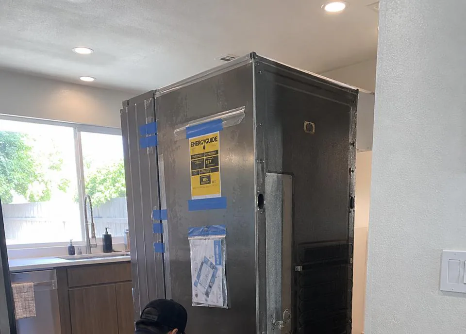 Appliance repair technician servicing a built-in refrigerator in an Irvine, California master-planned home